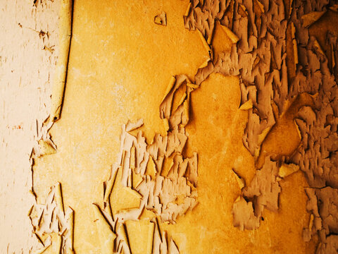 Old yellow orange painted wall with peeling off paint. Background texture for design.