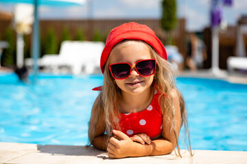 Child in swimming pool. Tropical vacation for family with kids. Little girl wearing red swimsuit...