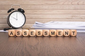 wooden blocks spelling 'ASSESSMENT' on a brown background
