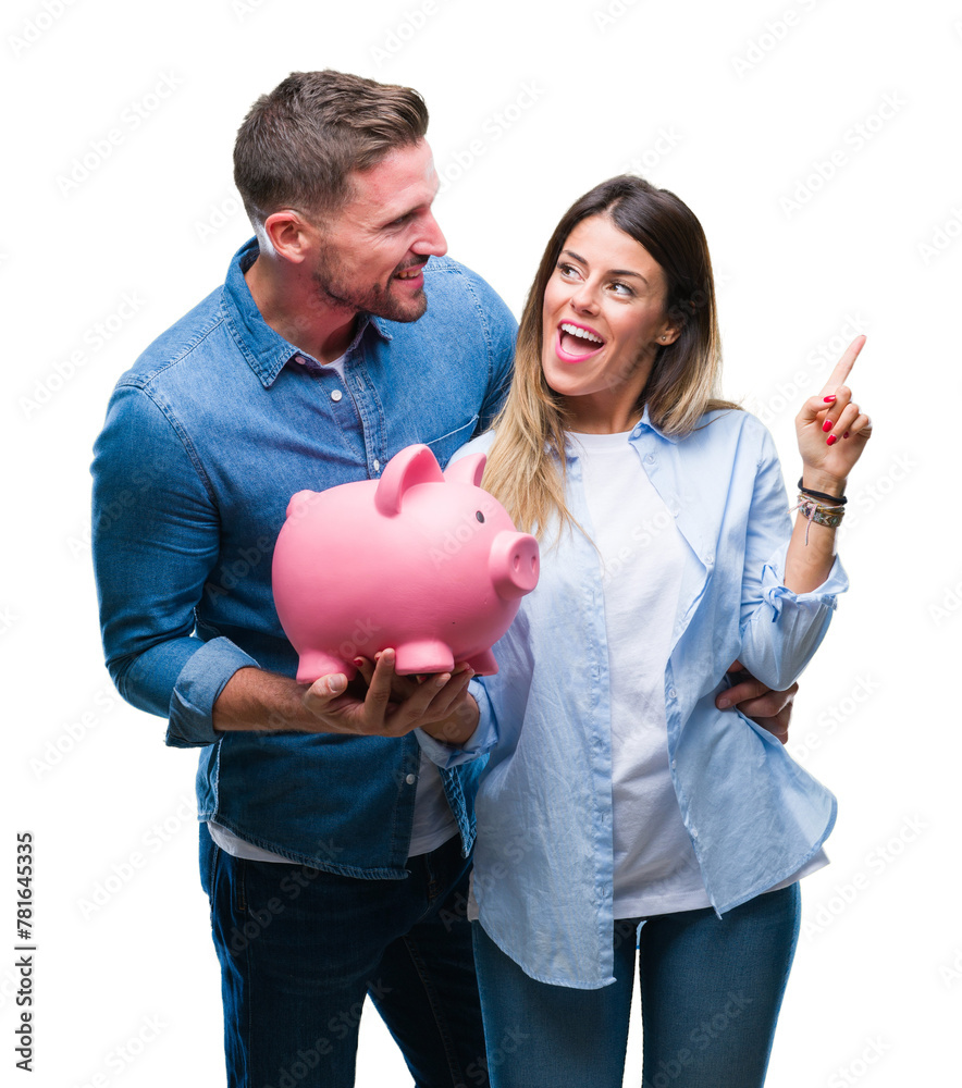 Canvas Prints Young couple in love holding piggy bank over isolated background very happy pointing with hand and finger to the side