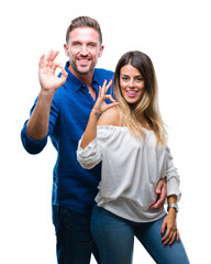 Young couple in love over isolated background smiling positive doing ok sign with hand and fingers....