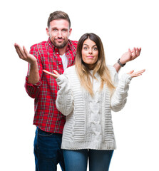 Young couple in love wearing winter sweater over isolated background clueless and confused...