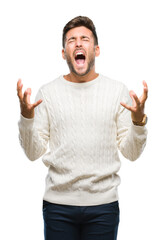 Young handsome man wearing winter sweater over isolated background crazy and mad shouting and yelling with aggressive expression and arms raised. Frustration concept.