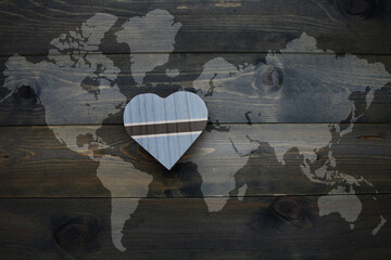 wooden heart with national flag of botswana near world map on the wooden background.