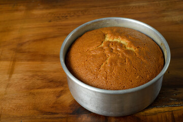 Freshly baked sponge cake cooling on wooden table.