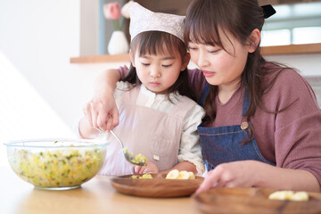 サラダを盛り付ける親子　女の子とお母さん - 781652721