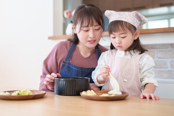 ご飯を盛り付ける親子　女の子とお母さん - 781652770