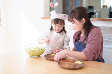 サラダを盛り付ける親子　女の子とお母さん - 781652902
