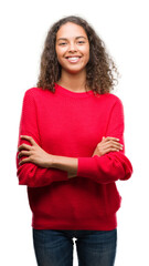 Young hispanic woman wearing red sweater happy face smiling with crossed arms looking at the...