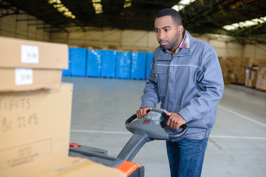 warehouse worker using electric pallet truck - Powered by Adobe