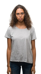 Beautiful young hispanic woman wearing glasses skeptic and nervous, frowning upset because of...