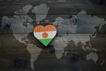 wooden heart with national flag of niger near world map on the wooden background.