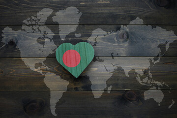 wooden heart with national flag of bangladesh near world map on the wooden background.