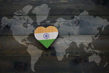 wooden heart with national flag of india near world map on the wooden background.