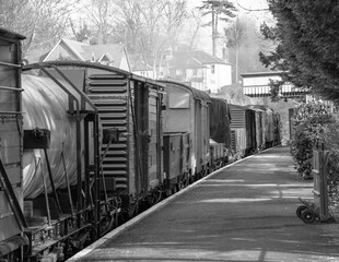Vintage steam train pulling goods wagons at an English station.