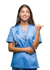 Young arab doctor surgeon woman over isolated background smiling with happy face looking and pointing to the side with thumb up.