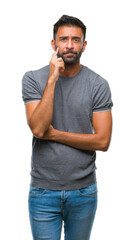 Fototapeta premium Adult hispanic man over isolated background with hand on chin thinking about question, pensive expression. Smiling with thoughtful face. Doubt concept.