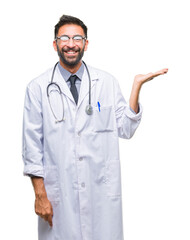 Adult hispanic doctor man over isolated background smiling cheerful presenting and pointing with...