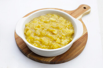 Mashed banana in bowl on white background.
