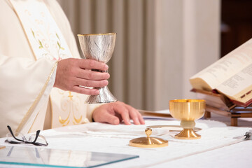priest holding chalice during sacred eucharist ceremony - obrazy, fototapety, plakaty