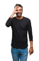 Fototapeta premium Adult hispanic man wearing glasses over isolated background doing ok gesture with hand smiling, eye looking through fingers with happy face.