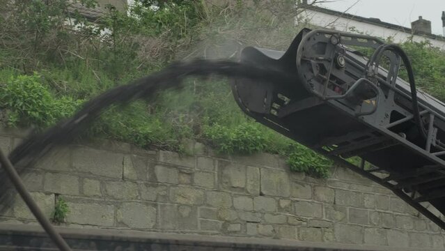A cold planer milling machine clearing old road tarmac and putting it in lorry via conveyor belt.