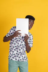 A man is holding a white laptop and looking at the camera