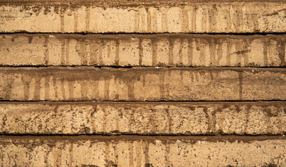 A cement surface with a brownish hue. The surface is covered in a layer of dirt and has a slightly worn appearance. The dirt appears to be a result of rain or other natural elements