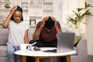 Stressed Young Couple Managing Finances, Looking At Their Laptop And Documents, Showing Concern And Worry, Home Interior