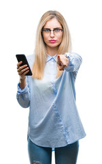 Young beautiful blonde business woman using smartphone over isolated background pointing with...