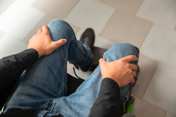 Man in wheelchair holding his legs, disabled person, feeling pain, stock photo