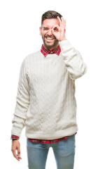 Fototapeta premium Young handsome man wearing winter sweater over isolated background doing ok gesture with hand smiling, eye looking through fingers with happy face.