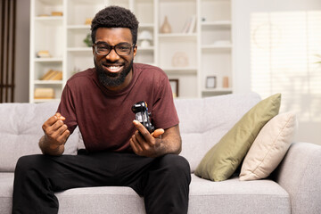 Happy Man With Glasses Holding Game Controller Winning Video Game At Home. Excitement, Entertainment, and Leisure Indoors Concept.