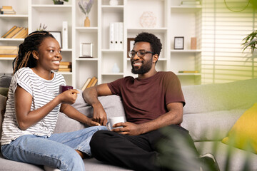 Happy Couple Relaxing and Sharing a Snack on the Couch in a Cozy Living Room, Embodying Comfort and Simple Everyday Joy at Home