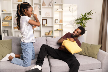 A Cheerful Young Couple Engaging in a Playful Pillow Fight in a Cozy Living Room Setting, Radiating Joy and Togetherness.
