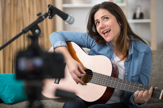 woman filming herself playing guitar and singing
