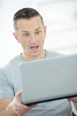 a surprised man with laptop - 781665503
