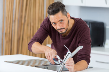 man installing kitchen faucet - 781665514