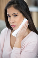 woman holding cloth on jaw to relieve toothache - obrazy, fototapety, plakaty