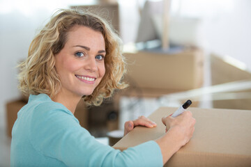 woman labeling moving box at home - obrazy, fototapety, plakaty