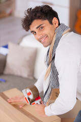 young man moving in new home and packing carboard boxes - 781665911