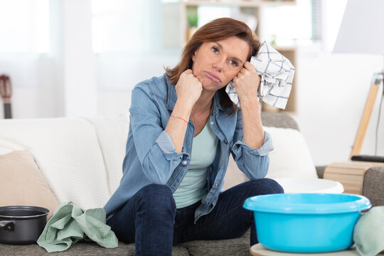 frustrated woman cleaning house sitting on the sofa