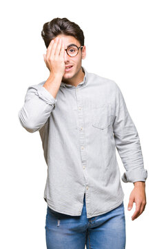 Young handsome man wearing glasses over isolated background covering one eye with hand with confident smile on face and surprise emotion.