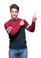 Young handsome man over isolated background smiling and looking at the camera pointing with two hands and fingers to the side.