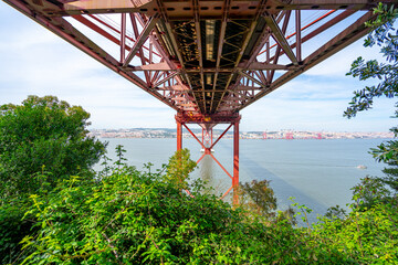 view from below the metallic structure platform of the 25 de Abril bridge from the city of...