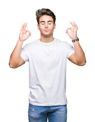 Young handsome man wearing white t-shirt over isolated background relax and smiling with eyes closed doing meditation gesture with fingers. Yoga concept.