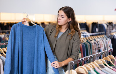 Casual young woman chooses summer clothes in a clothing store