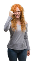 Young redhead woman angry and mad raising fist frustrated and furious while shouting with anger. Rage and aggressive concept.