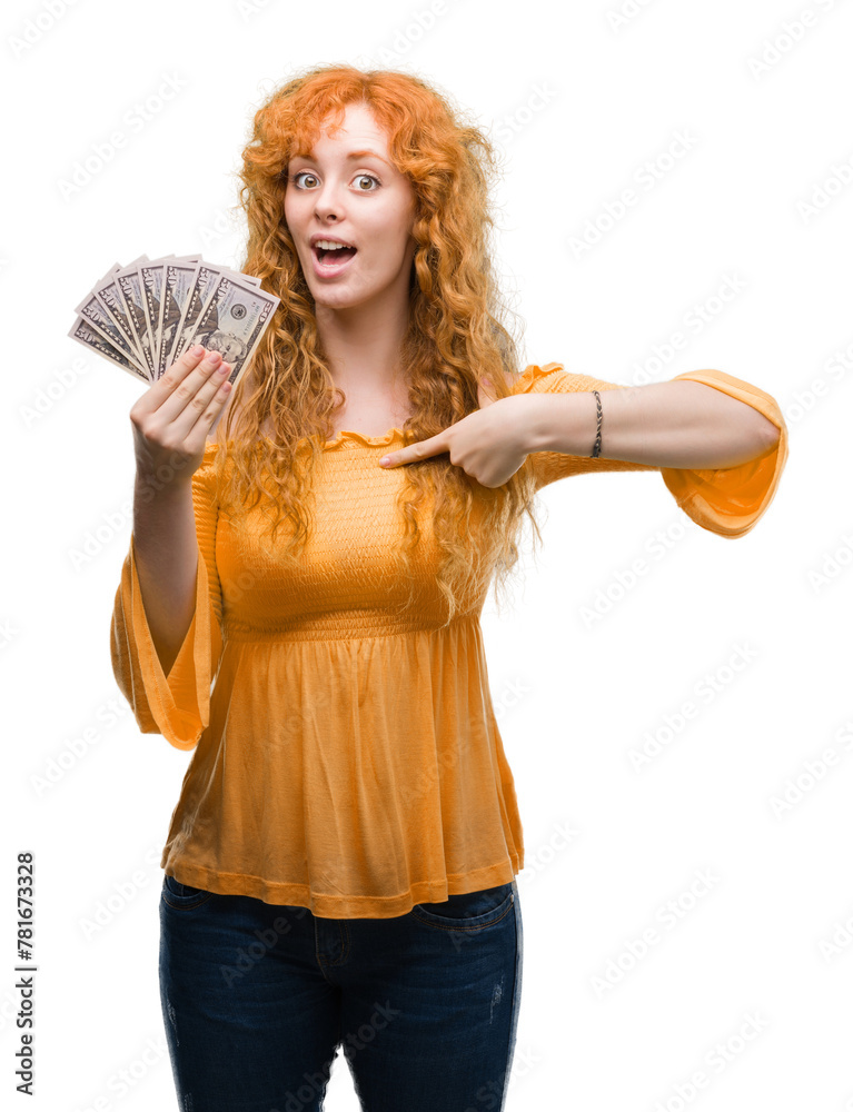 Sticker Young redhead woman holding dollars with surprise face pointing finger to himself