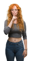 Young redhead woman asking to be quiet with finger on lips. Silence and secret concept.